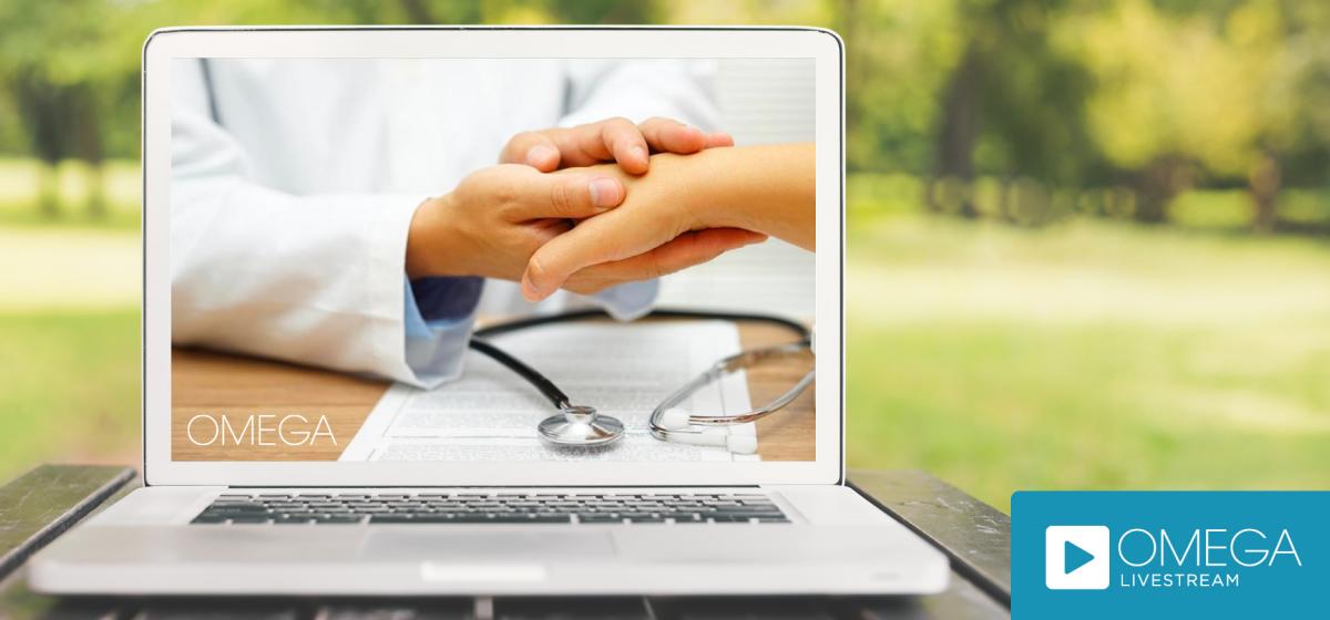Image of a doctor holding a patient's hand on a laptop screen outdoors
