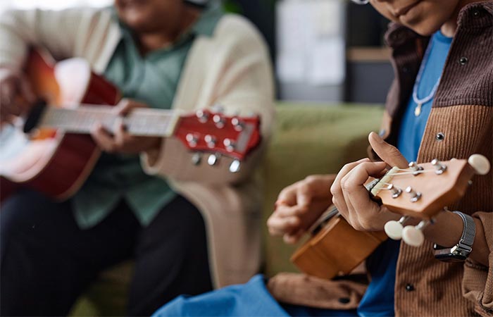 Two people playing ukeleles together