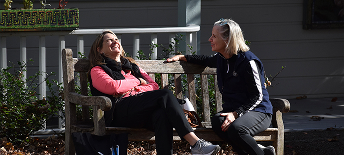 2 women sitting on bench, talking