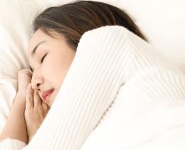 Peaceful woman sleeping in bed, illustrating steps to remember dreams and explore lucid dreaming.