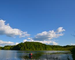 Blue sky and puffy white clouds reflected in lake