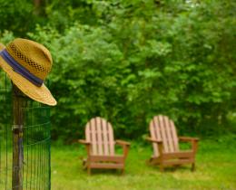 2 Adirondack chairs and a hat on a post