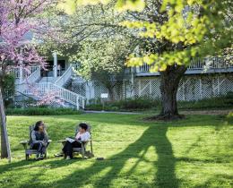 2 people sitting in Adirondack chairs under flowering spring trees