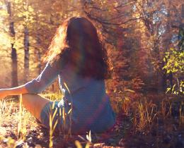 Woman meditating in forest in autumn