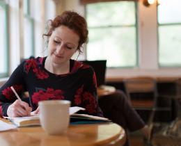 Woman sitting at the Omega Cafe and writing in a book