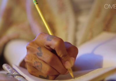 Tattooed hand writing poetry with pencil