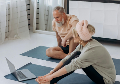 Mixed-gender couple doing yoga at home while looking at laptop