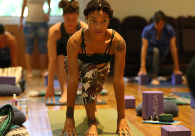 People doing yoga indoors, with mats and blocks.