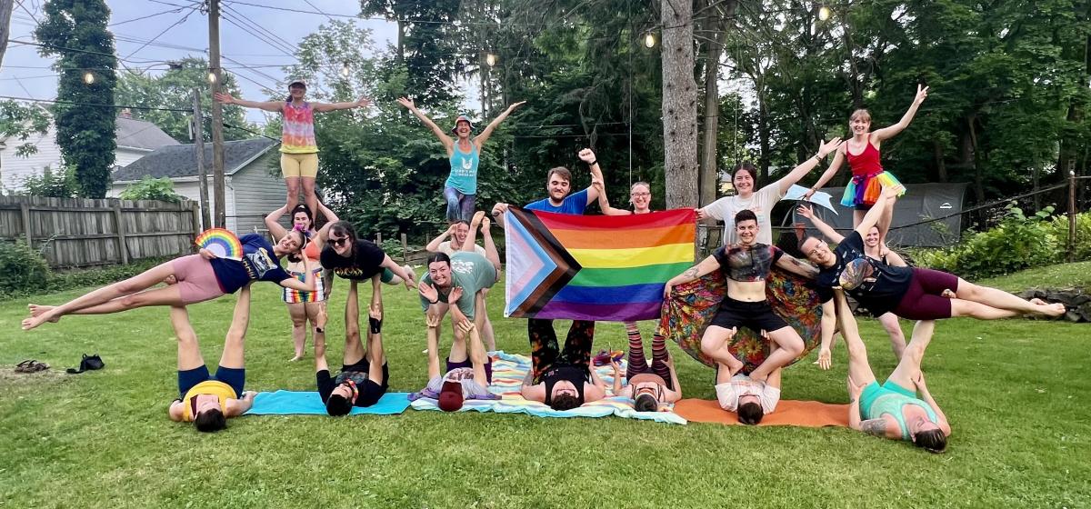 Participants in acro yoga class holding a pride flag