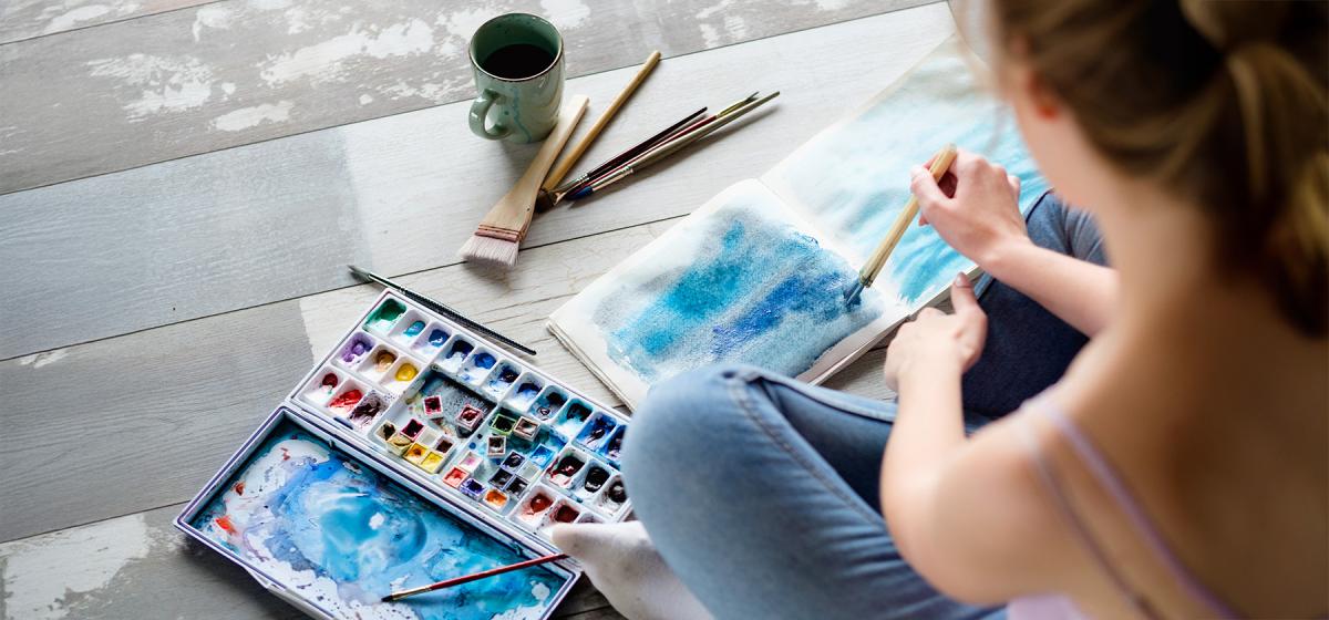 Person painting in a journal as part of an art therapy experience