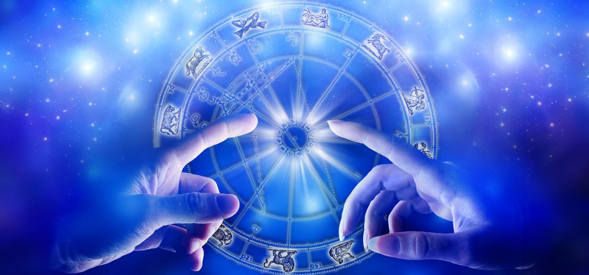 Two hands touching in front of an astrology chart