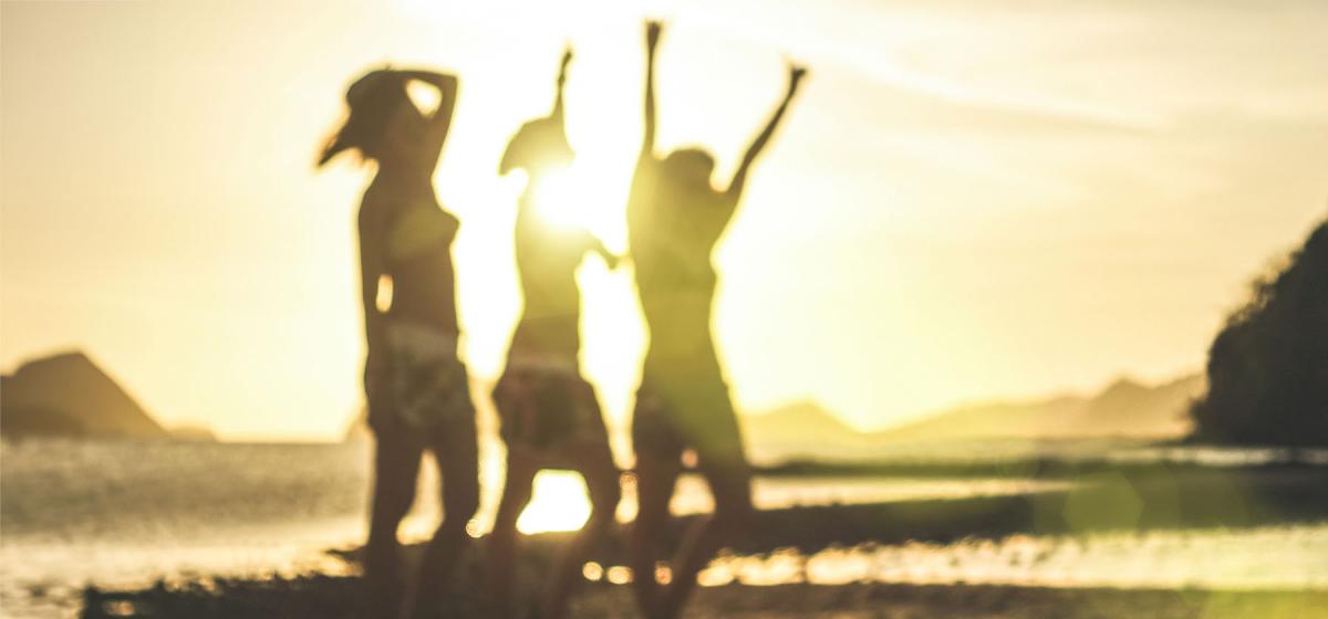 group of people dancing on beach at sunset