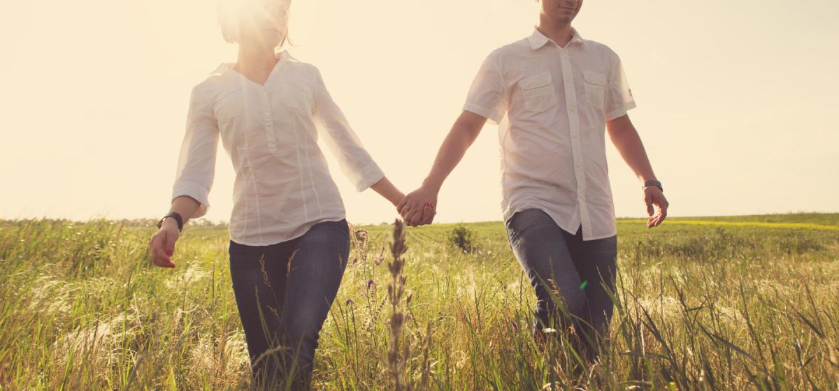 Couple holding hands walking through a field