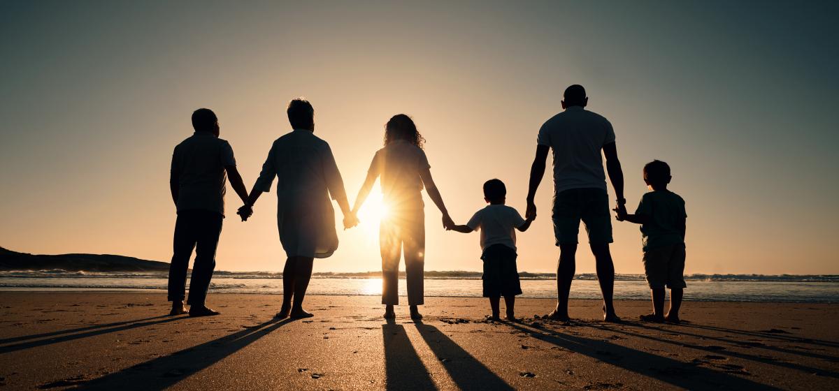 Multi-generational family standing together at sunset