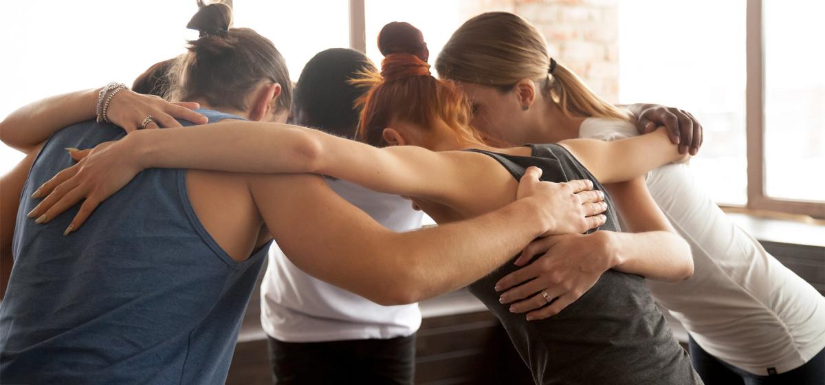 Group of people embracing in yoga studio