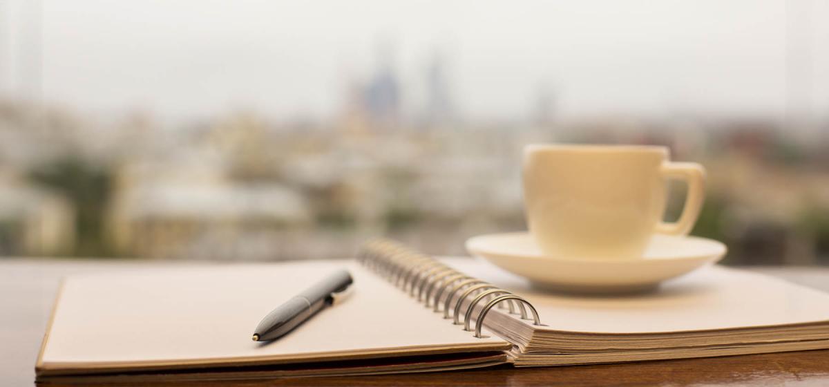 Notebook, pen and coffee cup outside