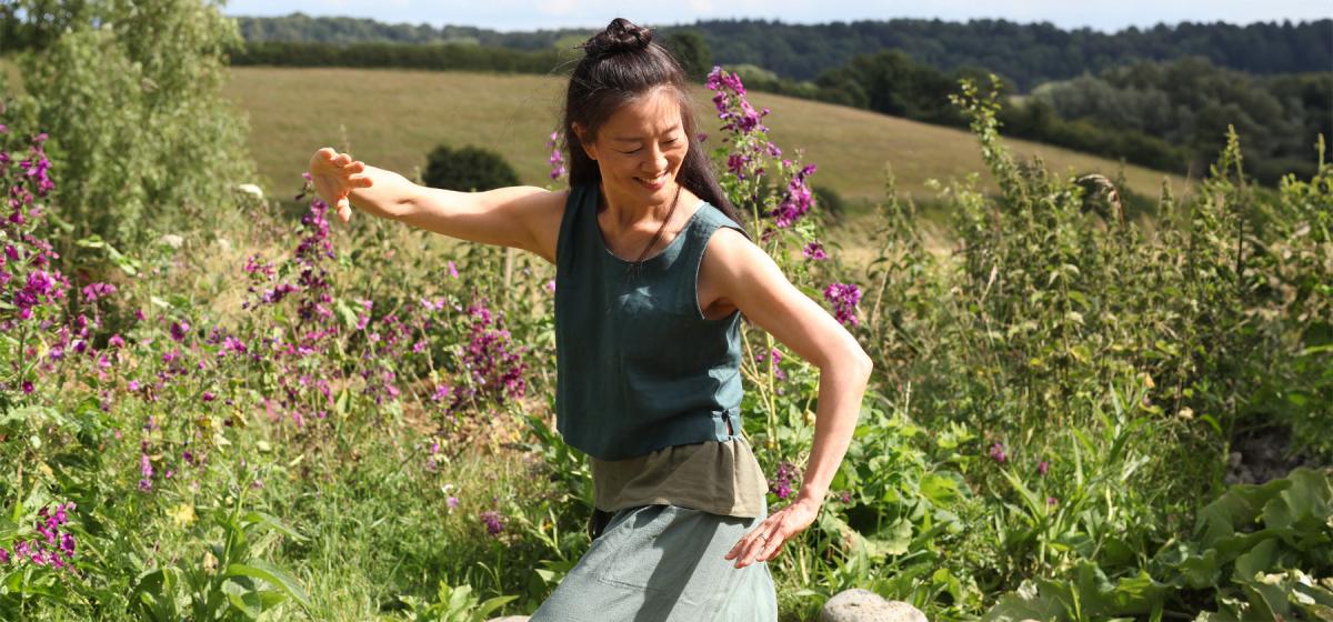 Mimi Kuo-Deemer doing qigong in a field