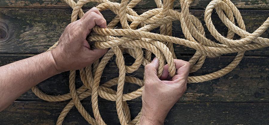 hands untying a messy rope