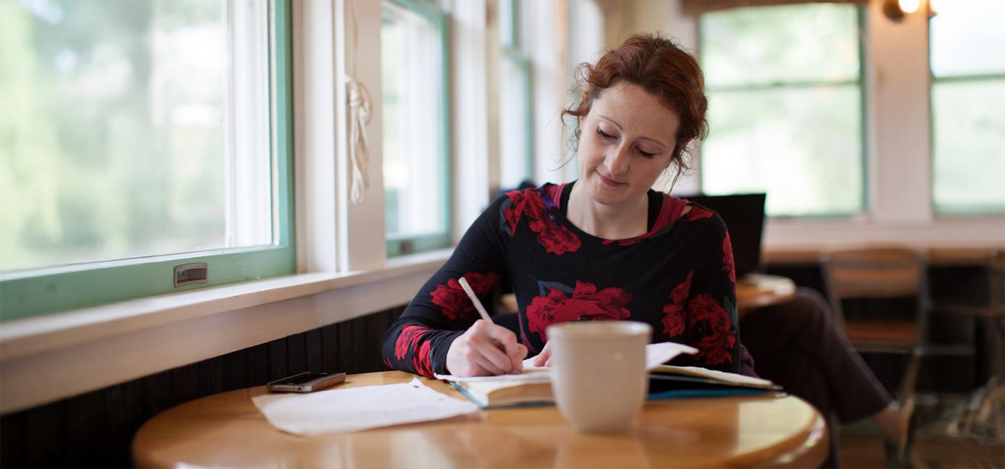 Woman sitting at the Omega Cafe and writing in a book